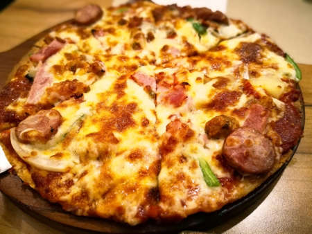 Six pieces of medium super deluxe pizza with stainless steel pizza peel, that are on the wooden tray. Selective focus and copy space.の写真素材