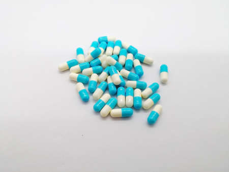 Medication concept. Indomethacin is generic name of drug, use for relief pain and reduce muscle inflammation. Many white-blue capsules isolated on white background, selective focus and copy space.の写真素材