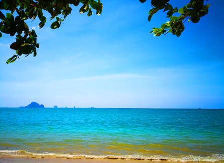 The beach of Southern Thailand. Small wave hit the shore. The sea is turquoise and the sky is clear, so you can see the small islands off the coast.の写真素材