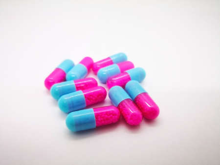 Medication and healthcare concept. Many pink-blue capsules of Itraconazole 100 mg., used to treat infections caused by fungus, which can invade any part of the body including the lungs, mouth or throat, toenails, or fingernails. White background, selective focus and copy space.の写真素材