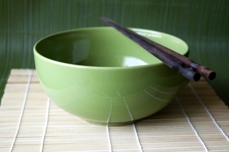Green bowl and chopsticks on Bamboo pad.の写真素材