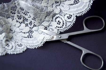 scissors cutting white lace on blue background.の写真素材