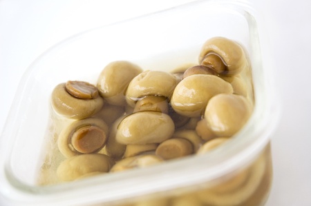 marinated champignons in glass box on white backgroundの写真素材