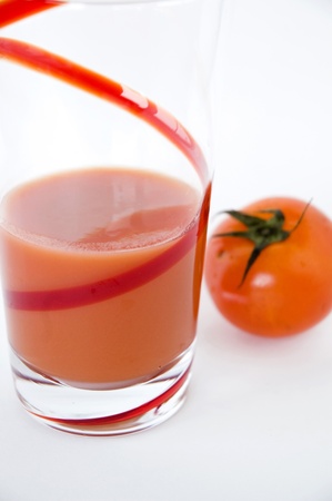 tomato with glass of juice on white backgroundの写真素材