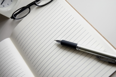 open blank notebook with pen and glasses on deskの写真素材