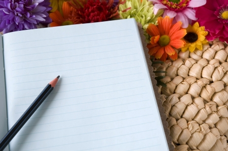 pencil put on notebook with flowers blooming backgroundの写真素材