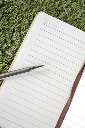 blank page of notebook with pen on grassの写真素材
