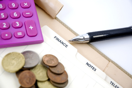 pen point to finance page with coins and pink calculatorの写真素材