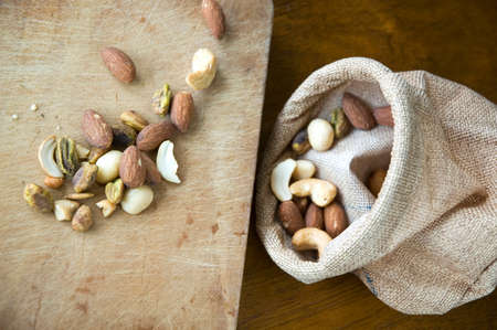 dried nuts on wooden with little sackcloth bag