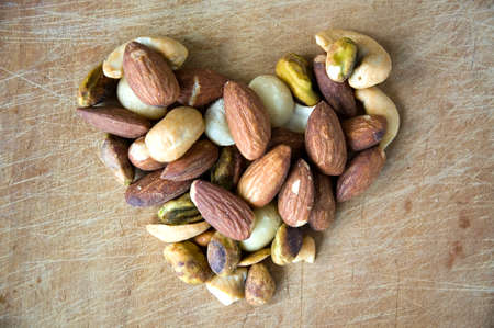 close up variety of nuts in heart shape on wooden boardの写真素材