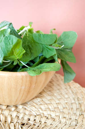 fresh spinach in wooden bowl with sweet pink background