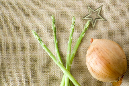 fresh asparagus with star on top with onion on sackcloth backgroundの写真素材