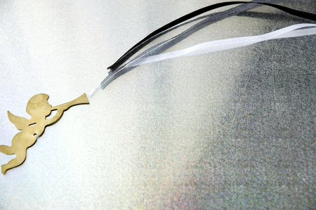 golden angel blowing ribbon on silver backgroundの写真素材