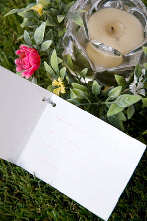 blank card put on green grass with flowers and candle