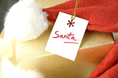 close up santa gift tag on golden box with santa red hatの写真素材