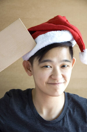 asian chinese looks wear santa hat and holding wooden blank board for textの写真素材