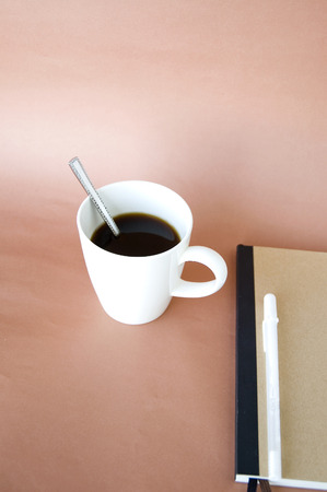 coffee in white cup with book on pink backgroundの写真素材