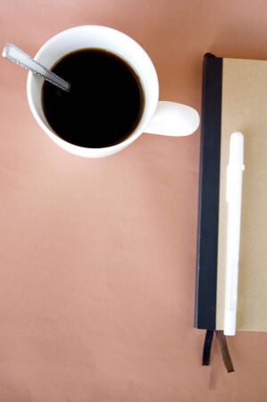 top of coffee cup with notebook on pink background with space for textの写真素材