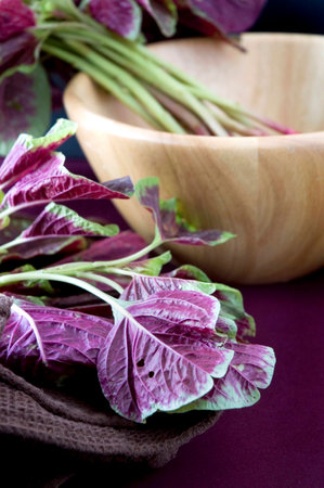 close up red spinach leaves with wooden bowl on background