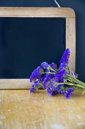 blank chalkboard with violet flowers put on wooden tableの写真素材
