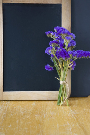 purple flowers bouquet put beside blank chalkboardの写真素材