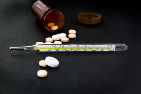 thermometer with pills and pills bottle on black backgroundの写真素材
