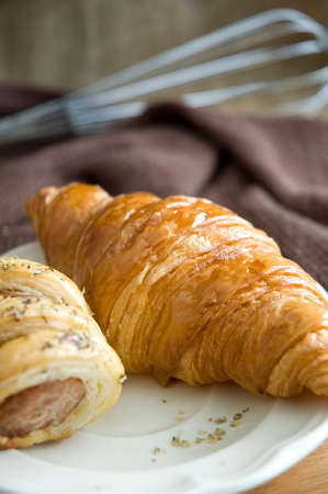 close up fresh golden croissant on dish with sausage rollの写真素材