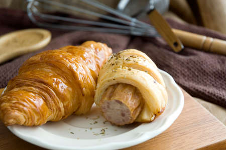 sausage roll and fresh croissant served on dishの写真素材