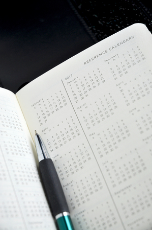 close up yearly calendar with pen on black backgroundの写真素材