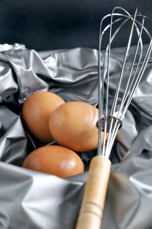 whisk put on eggs with silver color backgroundの写真素材