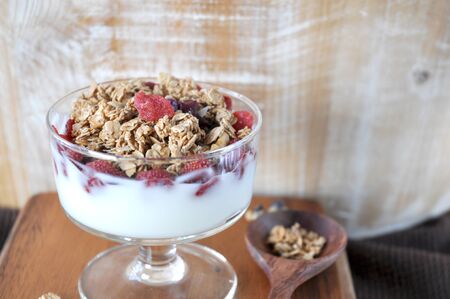 Granola mixed dried berry in yogurt glass on wooden background