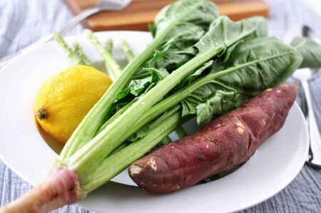 Fresh spinach with lemon and sweet potato on white dish