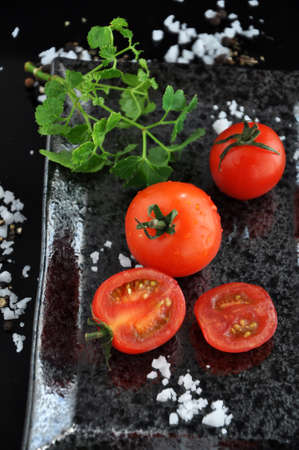 Fresh cherry tomato with sea salt on black trayの写真素材