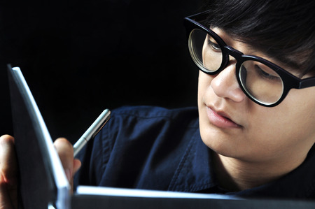 Asian working woman writing on her black notebookの写真素材