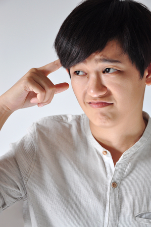 Young Asian woman point her finger to her head with stress face on white backgroundの写真素材