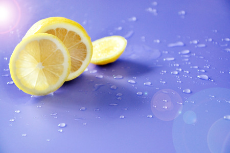 Lighting shine on fresh lemon with water drop on blue backgroundの写真素材