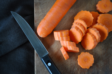 Top view of raw carrot cutting on wooden board with knifeの写真素材