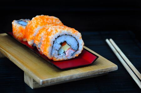 Sushi roll on red tray with chopsticks on black backgroundの写真素材