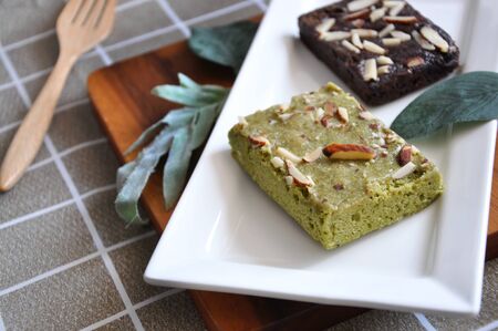 Matcha green tea brownie and dark chocolate brownie serve on white plate with space for textの写真素材