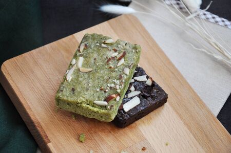  Stack of helathy matcha and dark chocolate brownies on wooden board