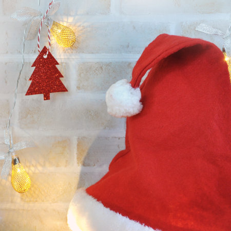 Red Santa hat with lighting decoration on the wall in square size imageの写真素材