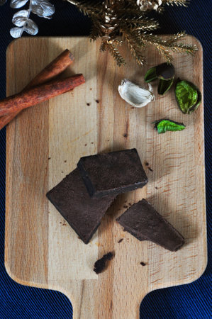 Top view of break pieces of dark chocolate brownie on wooden board with holidays decoration with space for textの写真素材