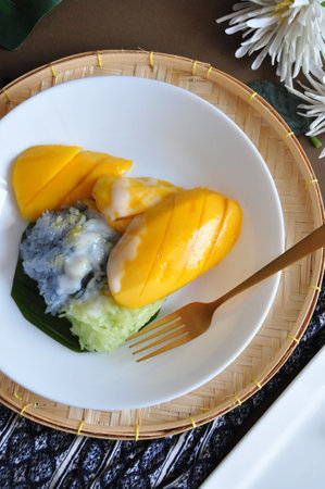 Top view of Thai dessert mango sticky rice with coconut milk on white dishの写真素材