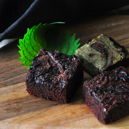 Close up homemade fudge brownie on wooden board with green leaf on dark backgroundの写真素材