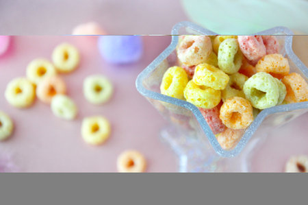 Top view of colorful fruit loops cereal in star shape cup with pastel color fruit loops on pink backgroundの写真素材