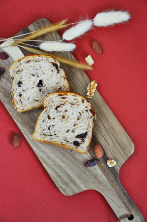 Top view of healthy bread dried cranberry with nuts put on wooden board on red backgroundの写真素材