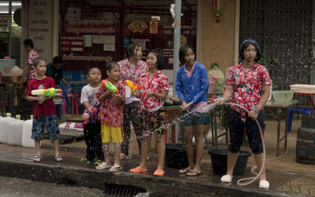 PHUKET, THAILAND - APRIL 13 2013: A group of kids on Sainamyen Road in Patong Beach wait for passing pedestrians and motor scooters to throw water on during Songkran, the traditional Thai New Year.のeditorial素材