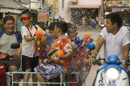 PHUKET, THAILAND - APRIL 13 2013: Father ferries his kids in a moped sidecar as they throw water at people during the Songkran Festival in Phuket. のeditorial素材