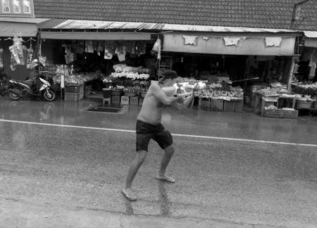 PHUKET, THAILAND APRIL 13: Foreign tourist aims and shoots his water gun at a passing motorist during Songkran in Phuket. のeditorial素材