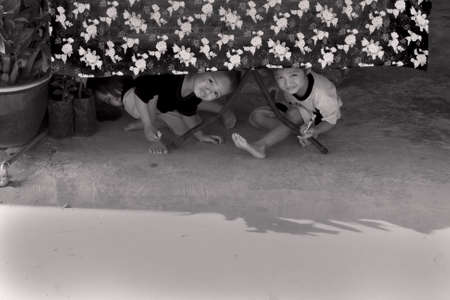 SABAH STATE, EAST MALAYSIA OCTOBER 1 2009: Three kids of the indigenous Kadezan people in Malaysian Borneo play under a picnic table at a highway rest stop along Highway A1. のeditorial素材